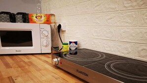 Een keuken met een magnetron, een fornuis en diverse keukengerei op het aanrecht.