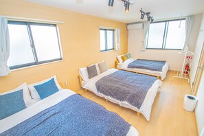 A hotel room with two beds, large windows, a hanging light fixture, and a fire extinguisher.