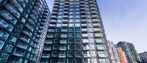 Un immeuble moderne à plusieurs étages, doté de nombreux balcons et de grandes fenêtres.