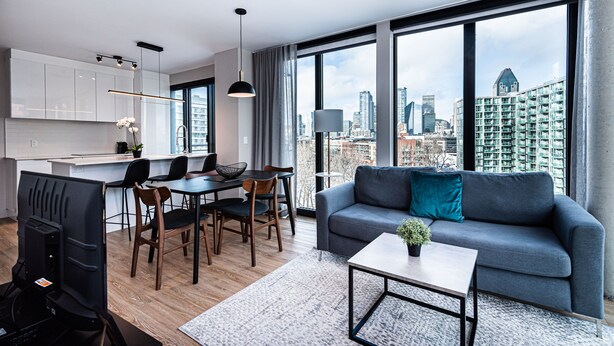 Um apartamento moderno com área de jantar, sala de estar com sofá e vista para a cidade.