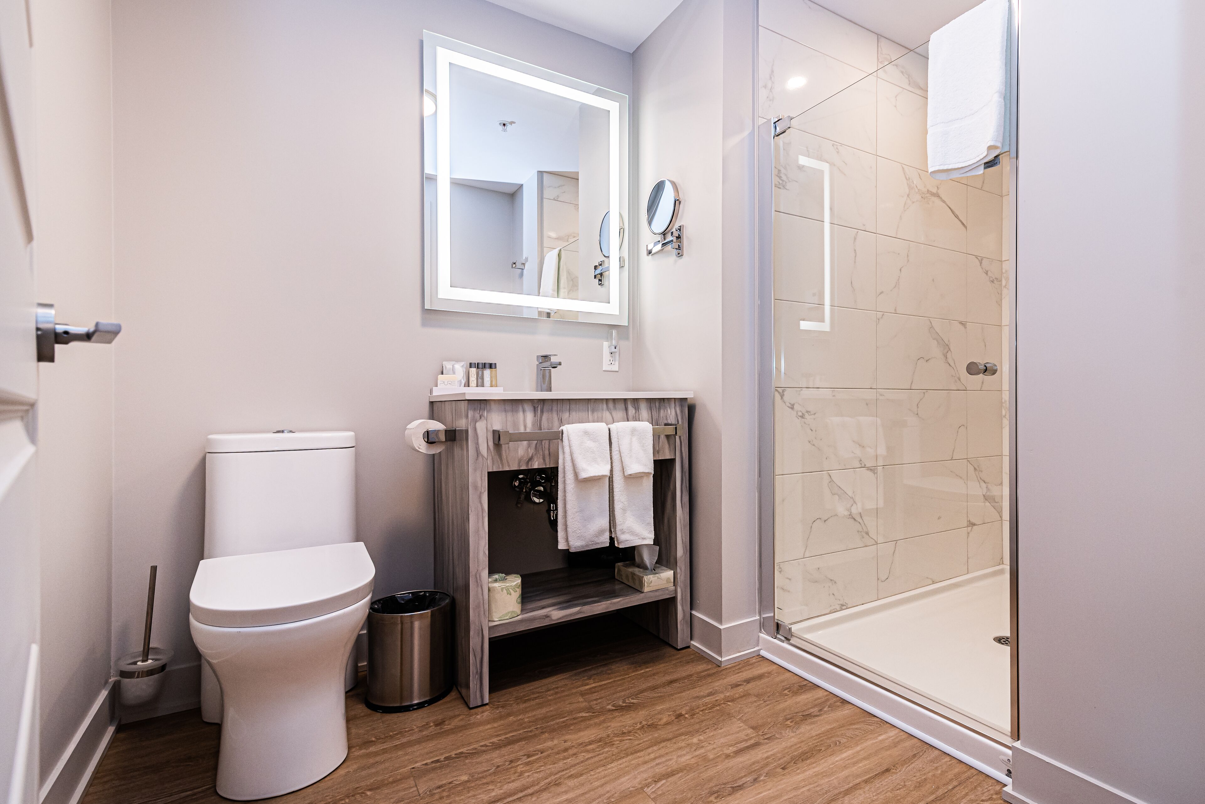 A modern bathroom with a toilet, vanity, and a glass shower enclosure.