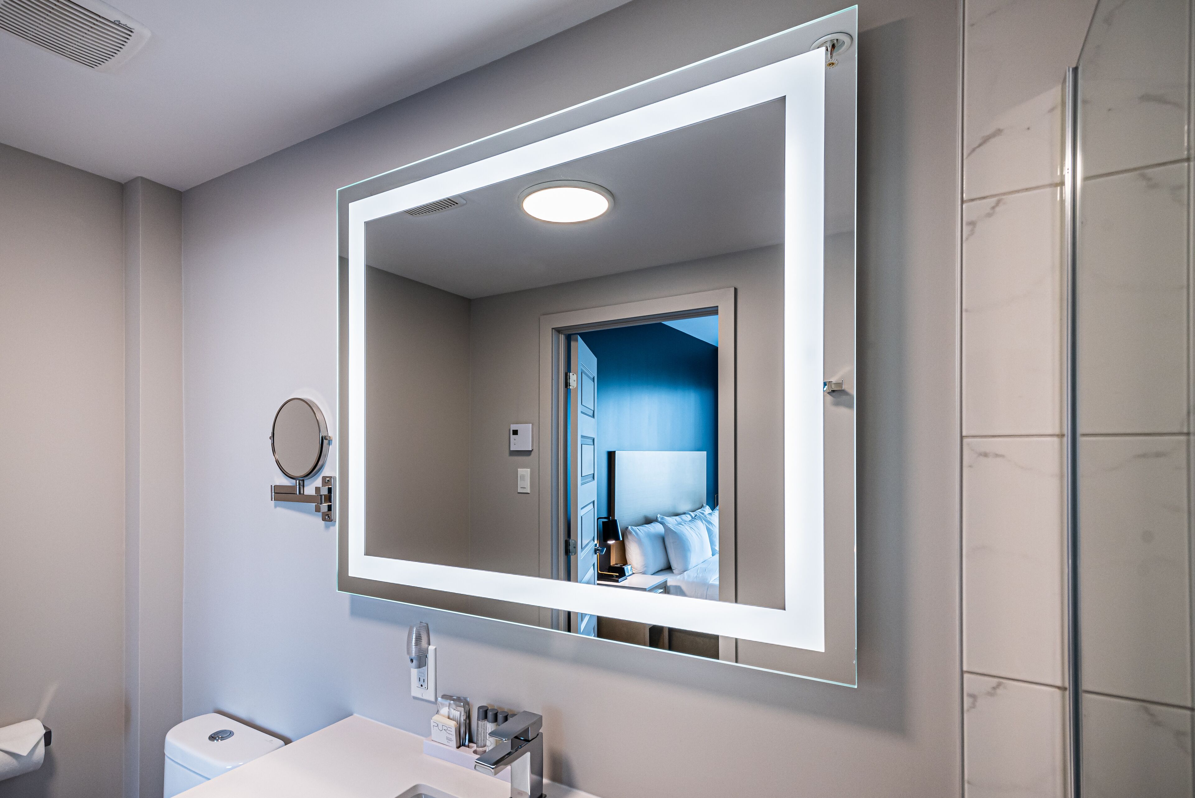 Un baño moderno con un espejo grande, un inodoro y un lavamanos.