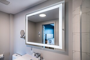 Un baño moderno con un espejo grande, un inodoro y un lavamanos.