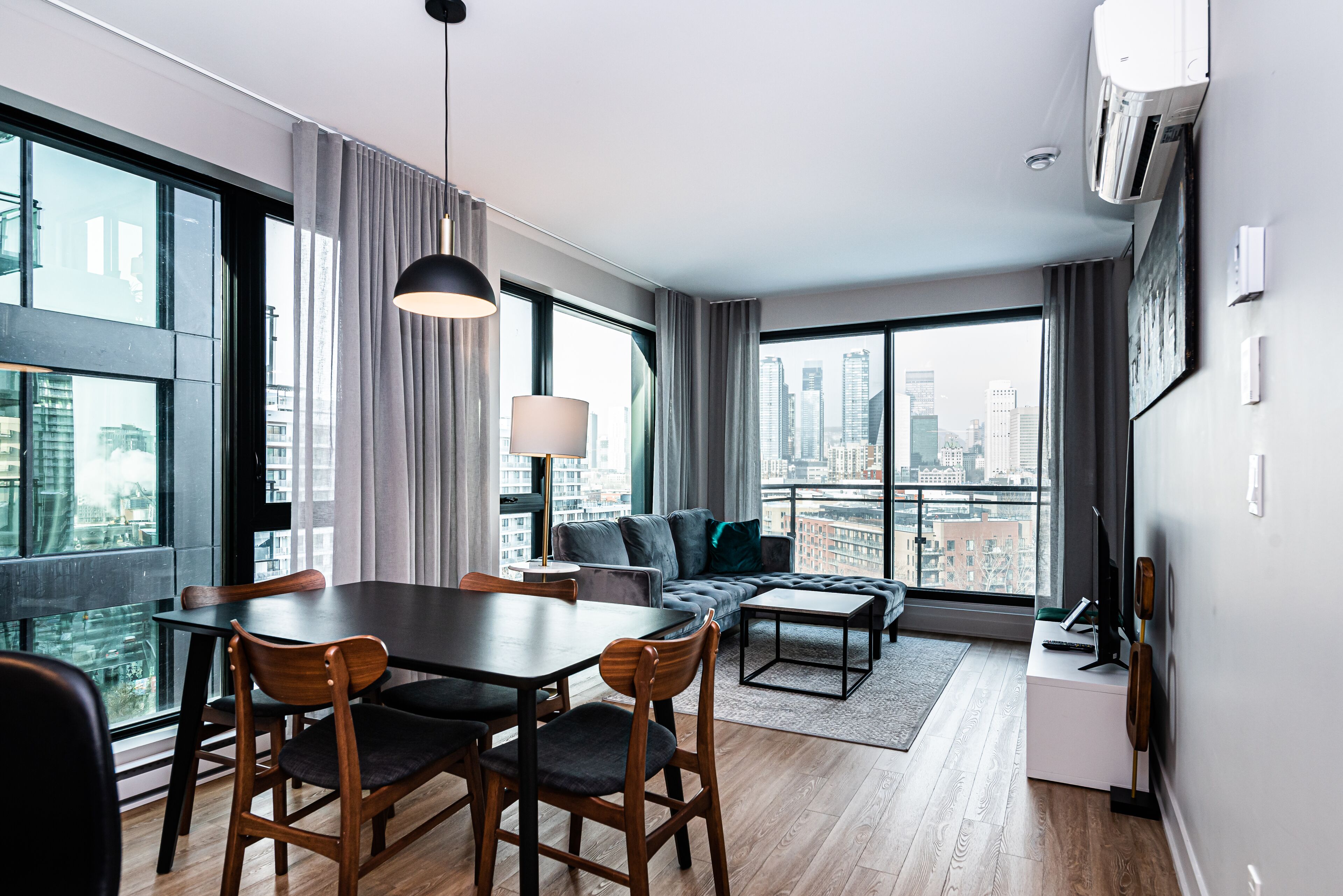 Un salon moderne avec un coin repas, de grandes fenêtres et une vue sur la ville.