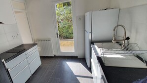 A compact kitchen with white cabinets, a black countertop, and a built-in oven.