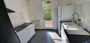 Una cocina compacta con armarios blancos, una encimera negra y un horno empotrado.