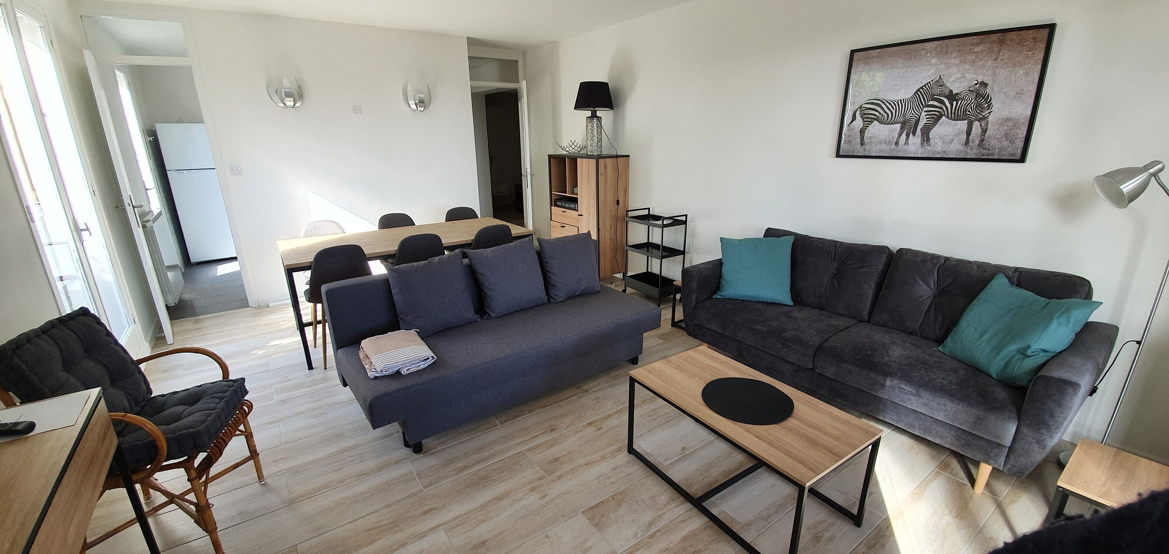Ein modernes Wohnzimmer mit einer Couch, einem Couchtisch und einem Essbereich mit Stühlen und einem Tisch.