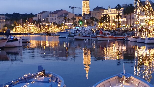 A marina at dusk with boats docked and illuminated by string lights.