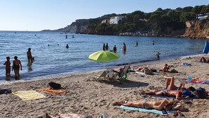 A beach with people sunbathing and swimming.