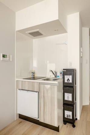 Uma cozinha compacta equipada com forno embutido, pia e pequeno frigorífico.