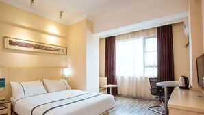 A hotel room with a bed, bedside table, lamp, chair, desk, and a television. - City Comfort Inn (Hezhou)