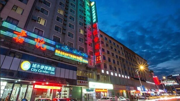 A multi-story hotel with illuminated signage, including a City Comfort Inn. - City Comfort Inn (Hezhou)