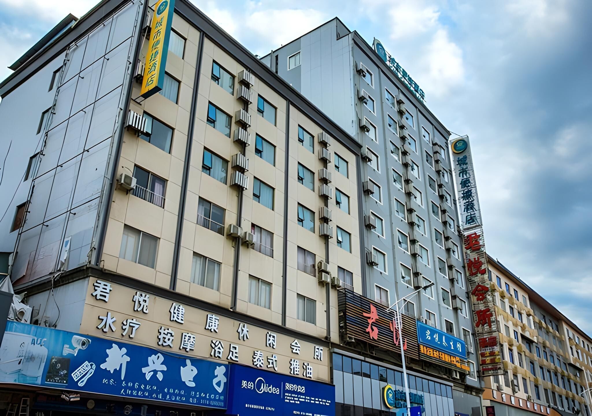 A multi-story hotel with a modern facade, multiple balconies, and various signage indicating amenities and services.