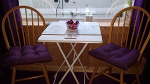Un pequeño comedor con dos sillas de madera y una mesa blanca.