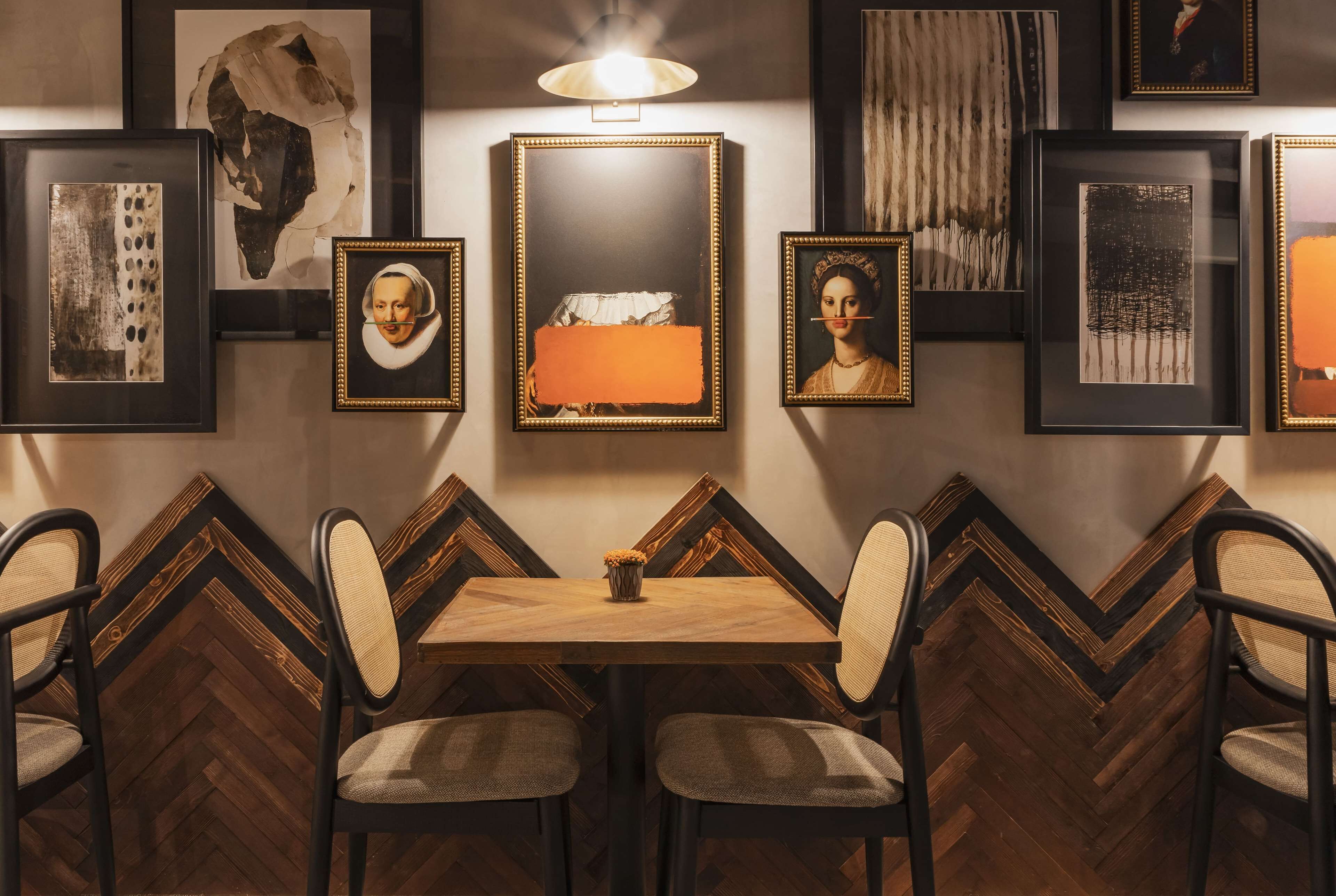 A dining area with a wooden table and chairs, surrounded by framed artwork on the walls.