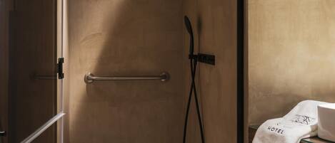 A modern shower area with a glass door, a towel rack, and a small shelf with a towel.