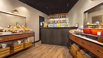 A breakfast buffet with wooden counters, a variety of food items, and a bar area with bottles and glasses.