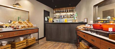 A breakfast buffet with wooden counters, a variety of food items, and a bar area with bottles and glasses.