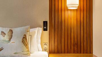 A hotel room with a wooden panel wall, a bed with white bedding, and a wall-mounted light fixture.