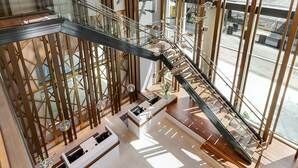 A modern interior with a glass railing, a wooden reception desk, and a staircase with a metal railing. - Margaritaville Vacation Club – Atlanta (Atlanta)