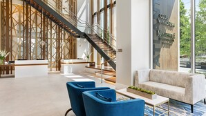 A modern lobby with a reception desk, blue chairs, a sofa, and a staircase. - Margaritaville Vacation Club – Atlanta (Atlanta)