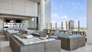 A rooftop lounge with wicker furniture, a bar area, and a view of the city skyline. - Margaritaville Vacation Club – Atlanta (Atlanta)