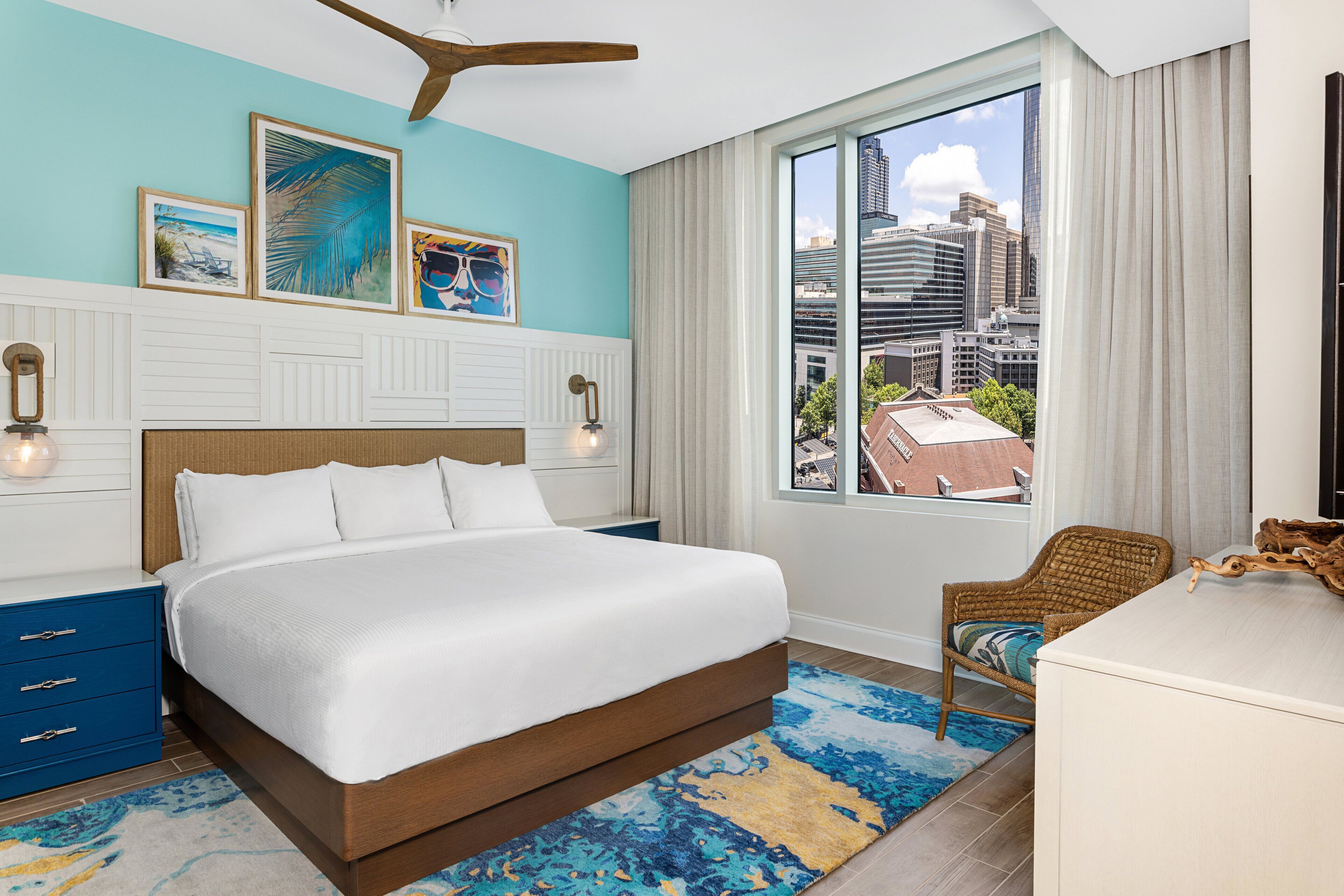 A modern hotel room with a large bed, a view of the city, and a window with curtains.