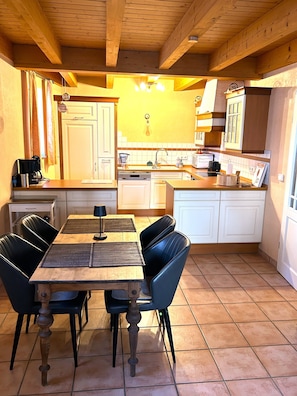 Una cocina con una mesa de comedor, sillas y una cafetera.