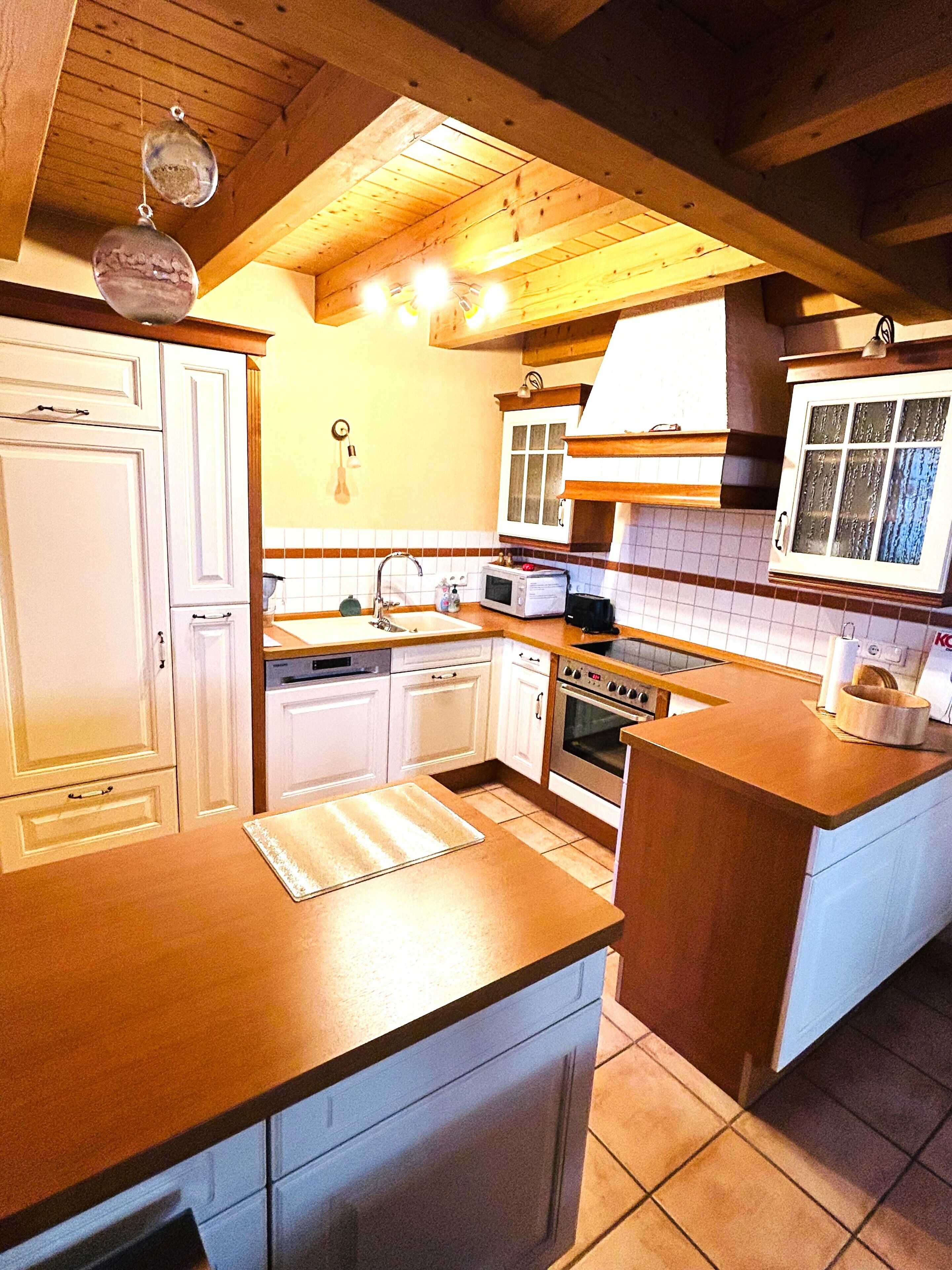 Une cuisine avec des meubles de rangement en bois, un four à micro-ondes, un four traditionnel et un évier.