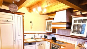 Una cocina con gabinetes de madera, microondas, horno y lavamanos.