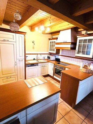 Una cucina con mobili in legno, un forno a microonde, un forno e un lavello.