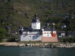 Un bâtiment qui ressemble à un château, doté de nombreuses tours et d’une tour centrale imposante, situé au bord d’une côte rocheuse.