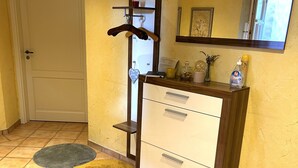 Un baño con un armario de madera, un espejo, un perchero y una puerta.