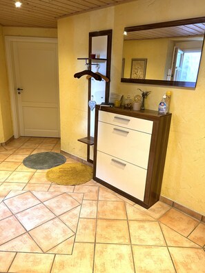Un bagno con un armadietto in legno, uno specchio, un porta asciugamani e una porta.
