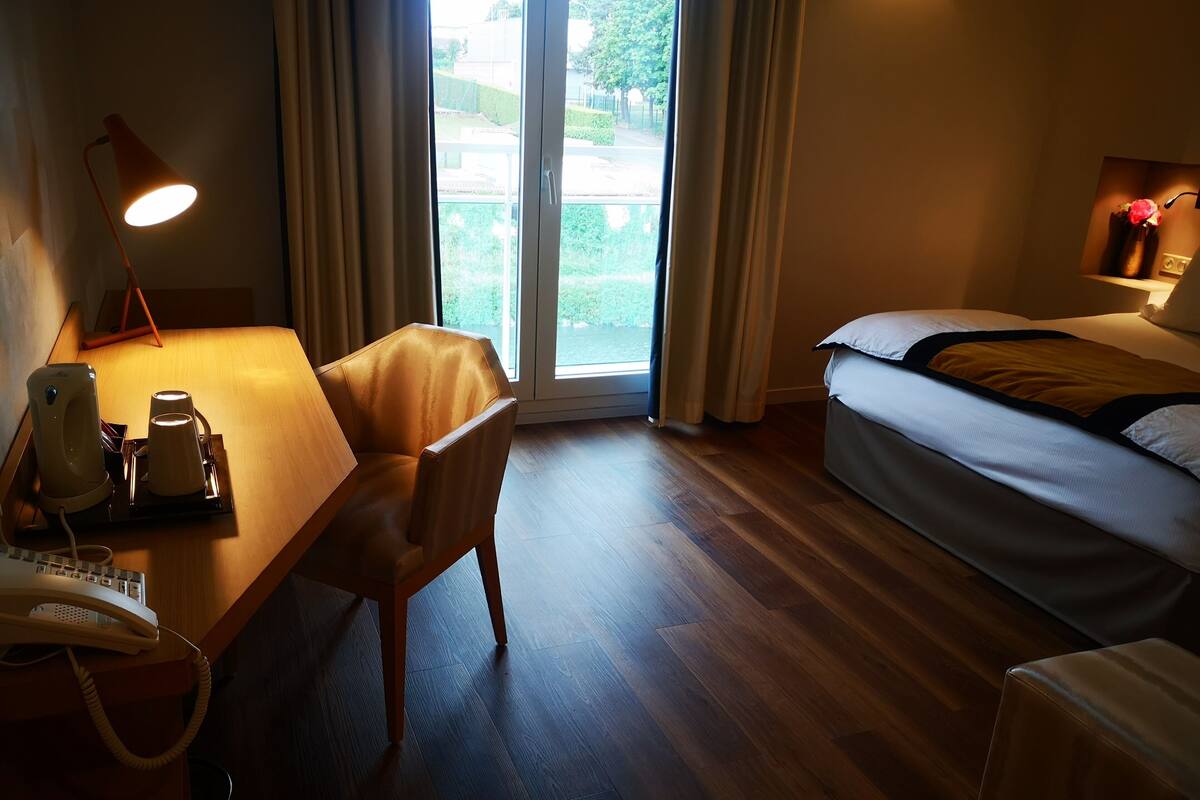 Habitación de hotel con escritorio, silla, cama y vistas por la ventana.