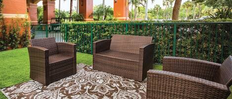 A patio area with wicker furniture and a patterned rug.