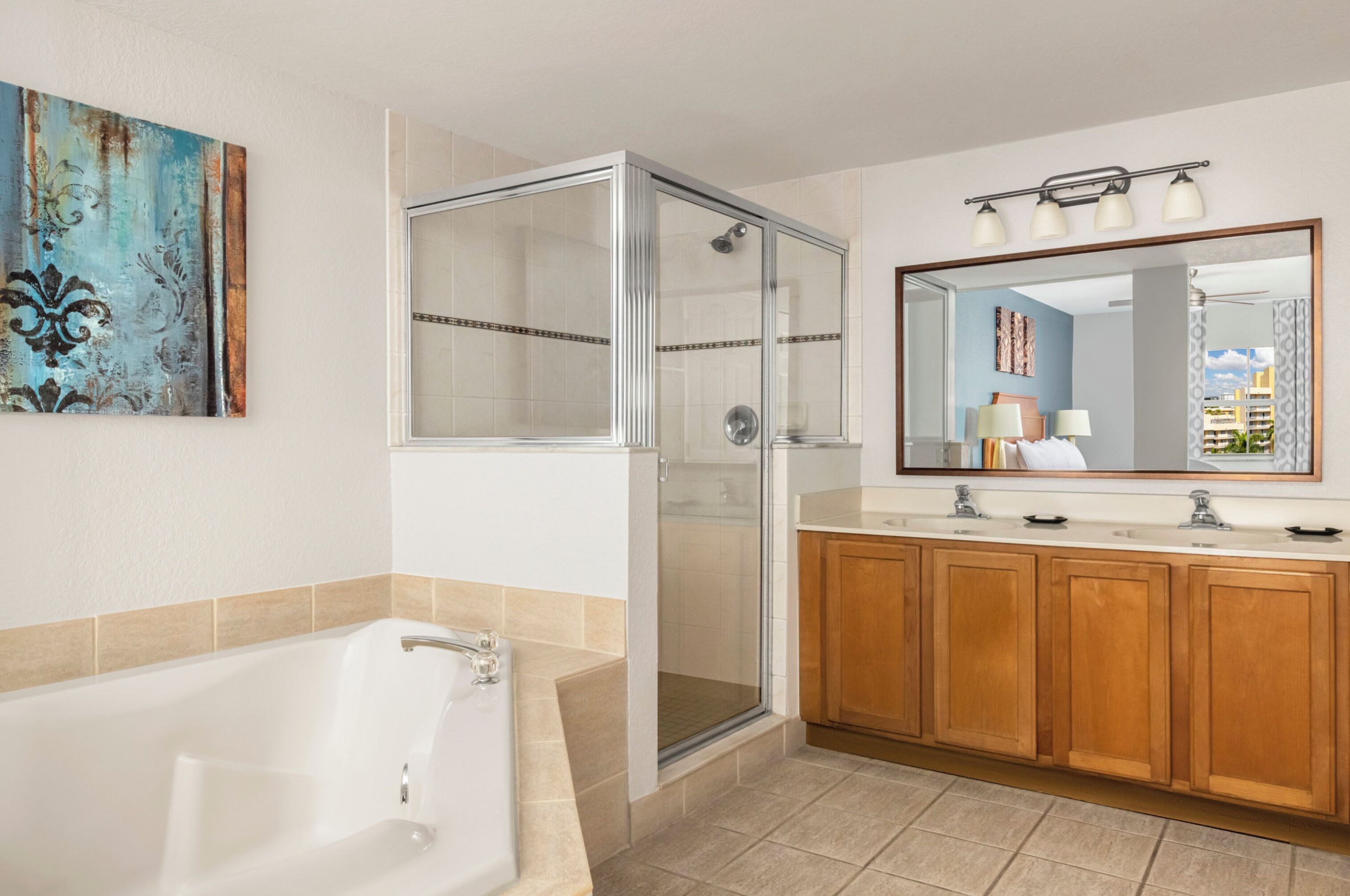Une salle de bain moderne dotée d’une douche à parois de verre, d’une grande baignoire, de meubles en bois et d’un miroir avec éclairage intégré.