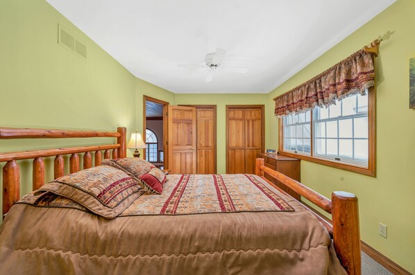 A bedroom with a wooden bed, a ceiling fan, and a window with a valance. - Awesome, 5 bedroom, private Boyne Falls home close to Boyne Mountain. (Boyne Falls)