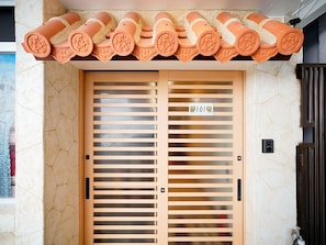 Una puerta doble con listones horizontales, un techo decorativo de terracota y un cartel con un oso y el número 101.