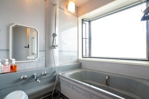 Ein Badezimmer mit Badewanne, Dusche, Waschbecken und einem Fenster mit Jalousien.