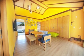 Een lichte, gele kamer met houten meubels, een groot raam en een kaart aan de muur.