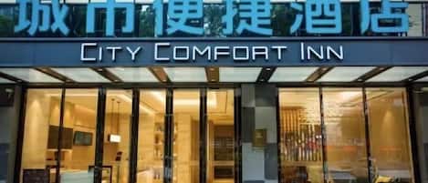 L’extérieur du City Comfort Inn se distingue par son design moderne, ses grandes portes vitrées et son intérieur visible, avec des espaces de détente et une décoration soignée.