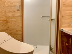 A bathroom with a toilet, wooden panel walls, a white door, and a small shelf with a towel. - Nonsmoking Frog House / Suwa-gun Nagano (Suwa-gun)