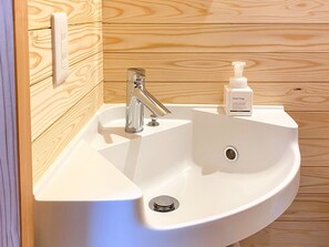 Ein weißes Waschbecken mit modernem Wasserhahn und einer Handseifen-Spender in einem Badezimmer mit Holzvertäfelung.
