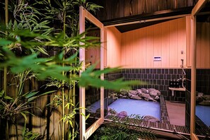 A traditional Japanese-style room with tatami flooring, a built-in shelf, and a small water feature.