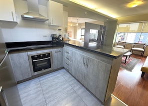 A modern kitchen with stainless steel appliances, a built-in oven, and a large island with a sink.