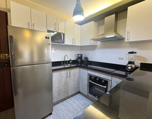 A compact kitchen with a stainless steel refrigerator, a microwave, a coffee maker, and a blender on the countertop. - Aparts4Days 1-Bedroom Loft in Downtown Miraflores Near the Malecón (Miraflores)