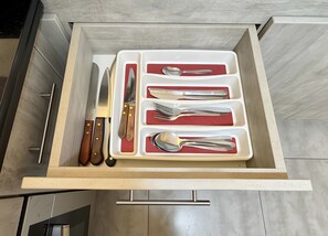 Un tiroir contenant un ensemble de couteaux, de fourchettes et de cuillères, rangés dans des compartiments.