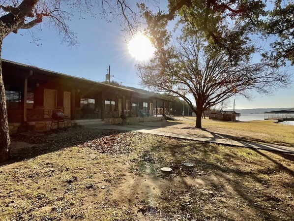 A building with a covered outdoor area, a tree, and a body of water in the background.