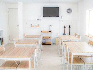 Une salle de classe aux murs blancs, avec un téléviseur à écran plat, une horloge et des guitares.